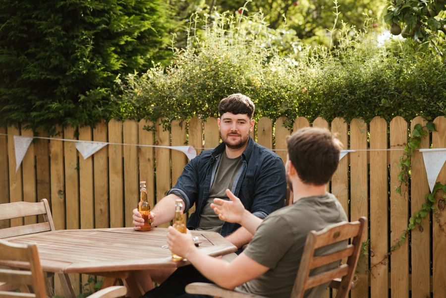 Gäste sitzen gemütlich im Gastgarten zusammen